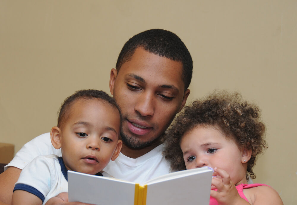 engaging toddlers to read - father reading with his toddler son and daughter
